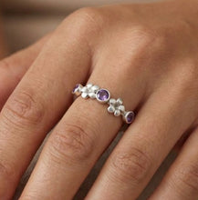 Load image into Gallery viewer, Close-up of a hand wearing a silver ring with purple gemstones on a beige background