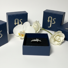 Load image into Gallery viewer, Silver ring in a blue box with 'AS' branding, surrounded by white flowers on a light gray background.