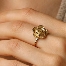 Load image into Gallery viewer, Gold rose-shaped ring on a person's finger with a blurred background