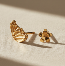 Load image into Gallery viewer, Gold butterfly and flower earrings on a beige fabric background